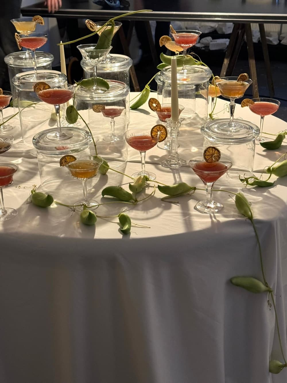 Ronde tafel met wit kleed, cocktails en glazen met groene blaadjes