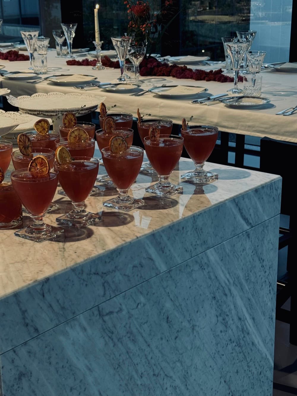 Lange marmeren tafel met rijen rode cocktails en gedekte couverts